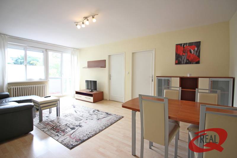 **BEZ PROVÍZIE**3-IZBOVÝ BYT S BALKÓNOM A LOGGIOU NA PALISÁDACH**      - Obývacia izba v 3-izbovom byte s podlahou s dreveným dekorom, sedačkou a jedálenským stolom.