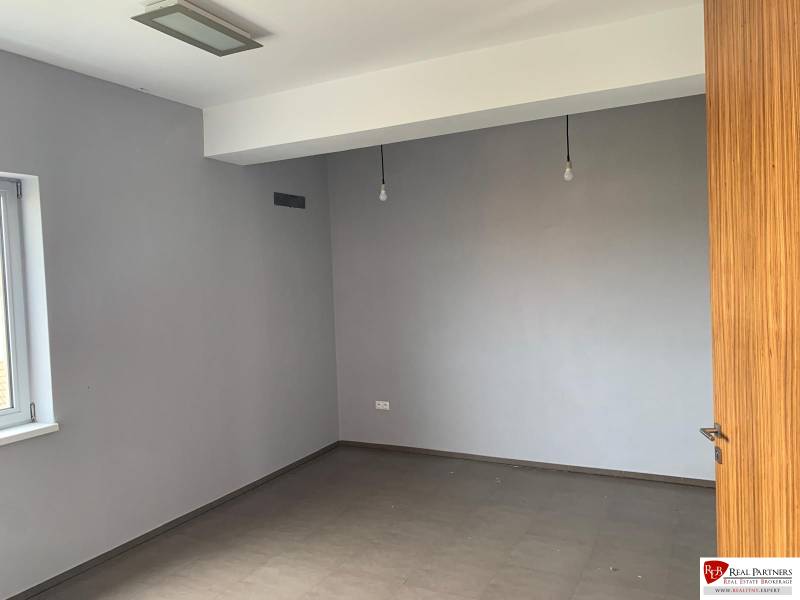 Predaj modernej administratívnej budovy v Bratislave, okres II - Prázdna izba s bielymi stenami a drevenými dverami. Nepoužívaná budova.