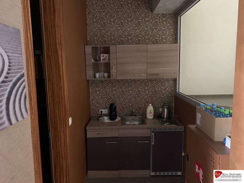 Predaj modernej administratívnej budovy v Bratislave, okres II - Malá kuchynka s mozaikovým obkladom, umývadlom, skrinkami a spotrebičmi v budove.