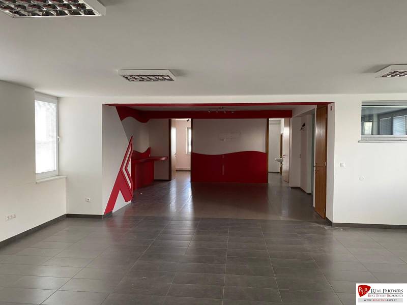 Predaj modernej administratívnej budovy v Bratislave, okres II - Priestranný interiér s červenými detailmi, vhodný pre kancelárie v modernej budove.