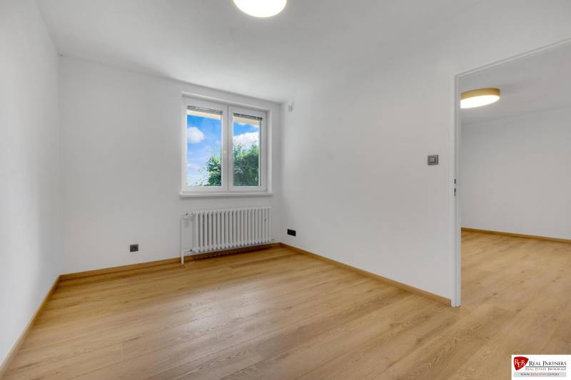 ,Prenájom moderný 3 izb. dom, Sološnícka ul,124 m2, Karlova Ves - Prázdna izba s podlahou s dreveným dekorom v rodinnom dome, biele steny a okno.