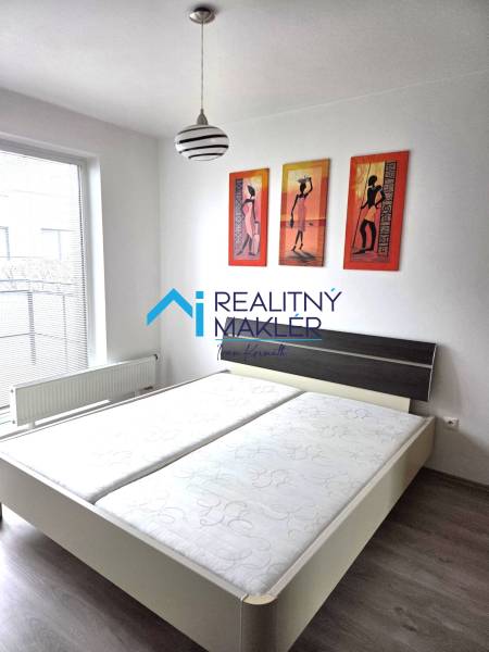 Prenajaté - 2.izbový byt s parkovaním v obci Hviezdoslavov - Spálňa s manželskou posteľou, lampou a obrazmi v 1-izbovom byte.