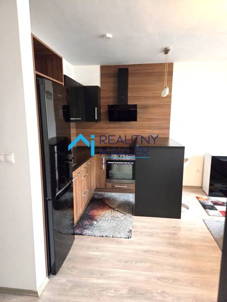 Prenajaté - 2.izbový byt s parkovaním v obci Hviezdoslavov - Kuchyňa v 1-izbovom byte s tmavým nábytkom a podlahou s dreveným dekorom.