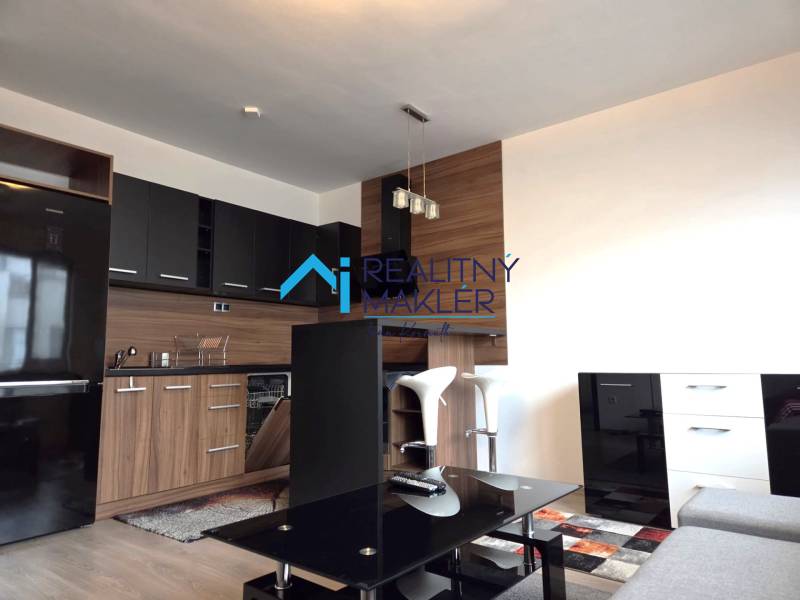 Prenajaté - 2.izbový byt s parkovaním v obci Hviezdoslavov - Kuchyňa v 1-izbovom byte s čiernymi skrinkami, podlaha s dreveným dekorom.