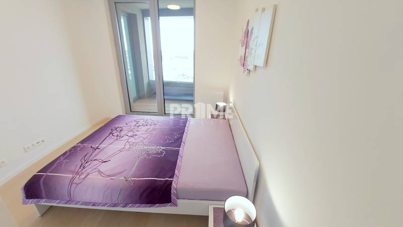 JEDINEČNÝ 2i byt, NOVOSTAVBA, KLÍMA, VÝHĽAD, PARKING, SKY PARK - Posteľ s fialovým povlečením, stolík a lampa v 2-izbovom byte.