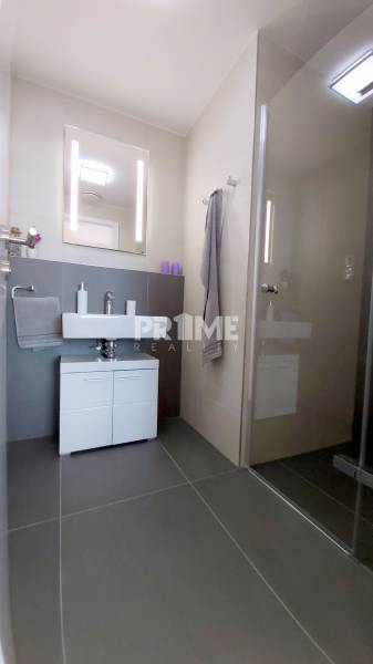 JEDINEČNÝ 2i byt, NOVOSTAVBA, KLÍMA, VÝHĽAD, PARKING, SKY PARK - Kúpeľňa so sprchovacím kútom, svetlým obkladom a umývadlom v 2-izbovom byte.