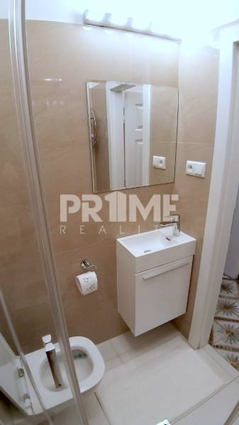 Pekný 2i byt, REKONŠTRUKCIA, CENTRUM, Bukureštská ulica, Staré Mesto - Kúpeľňa so svetlými obkladmi, umývadlo a zrkadlo na Bukurešťskej v 2-izbovom byte.