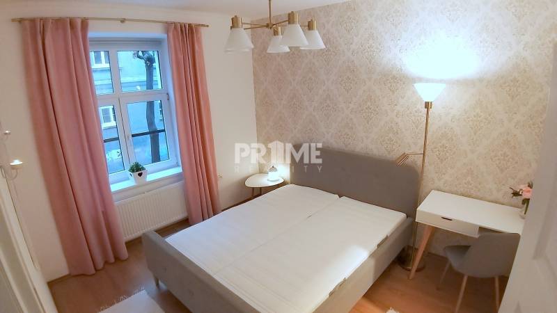 Pekný 2i byt, REKONŠTRUKCIA, CENTRUM, Bukureštská ulica, Staré Mesto - Svetlá spálňa, na ulici Bukurešťská, s posteľou, stolíkom a dekoratívnymi stenami v 2-izbovom byte.