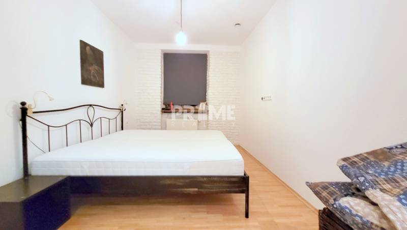 JEDINEČNÝ 2i byt, REKONŠT., 2 X .SAMOST.IZBA, Hviezdoslavovo nám.  - Spálňa s kovovou posteľou v 2-izbovom byte, svetlá stena a drevená podlaha.