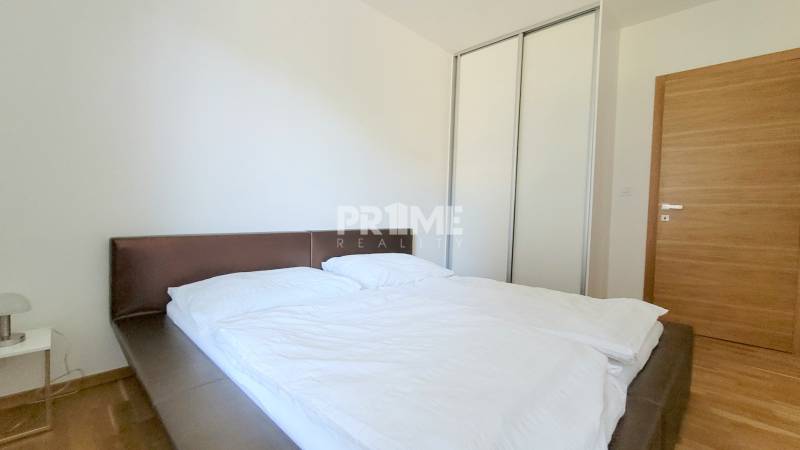 MODERNÝ 3i byt, CUBICON GARDENS, BALKÓN, PARKING, Rudolfa Mocka - Spálňa v 3-izbovom byte s veľkou posteľou, skriňou a podlahou s dreveným dekorom.