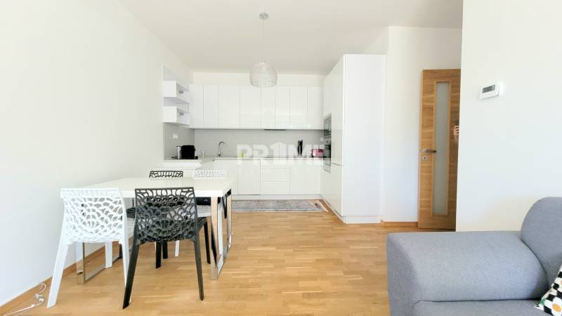 MODERNÝ 3i byt, CUBICON GARDENS, BALKÓN, PARKING, Rudolfa Mocka - Kuchyňa so stolom a stoličkami, podlaha s dreveným dekorom v 3-izbovom byte.