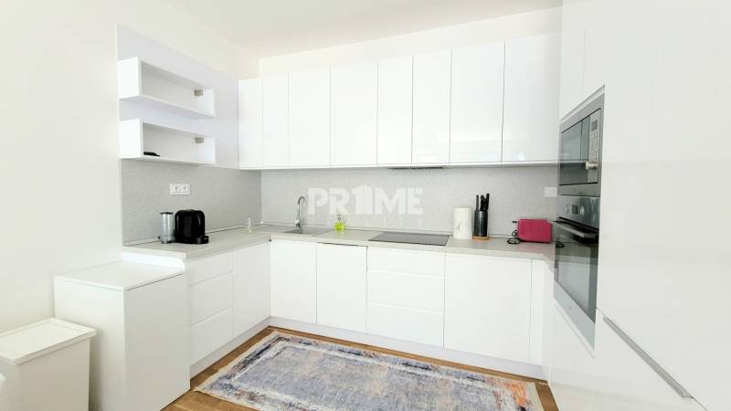 MODERNÝ 3i byt, CUBICON GARDENS, BALKÓN, PARKING, Rudolfa Mocka - Kuchyňa v 3-izbovom byte s bielymi skriňami a podlahou s dreveným dekorom.