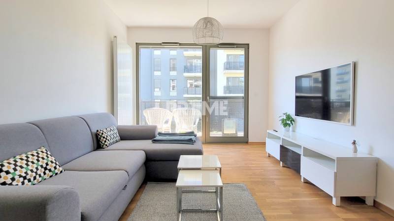 MODERNÝ 3i byt, CUBICON GARDENS, BALKÓN, PARKING, Rudolfa Mocka - Obývačka v 3-izbovom byte s pohovkou, podlahou s dreveným dekorom a terasou.