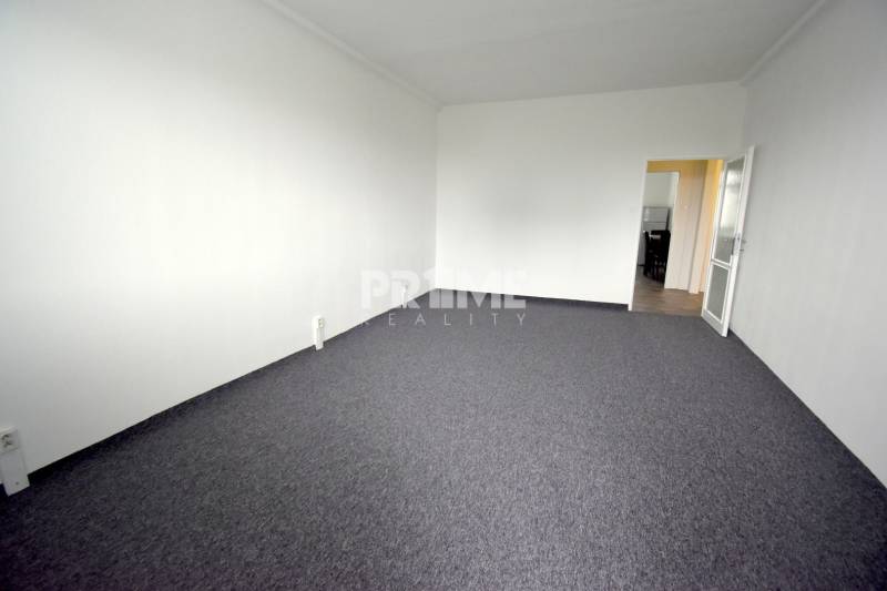 Pekný 3i byt, 3 x NEPRIECH.IZBA, BALKÓN, Radarová ulica, Ostredky - Miesto na sedenie v 3-izbovom byte s bielymi stenami, otvorenými dverami a tmavým kobercom.