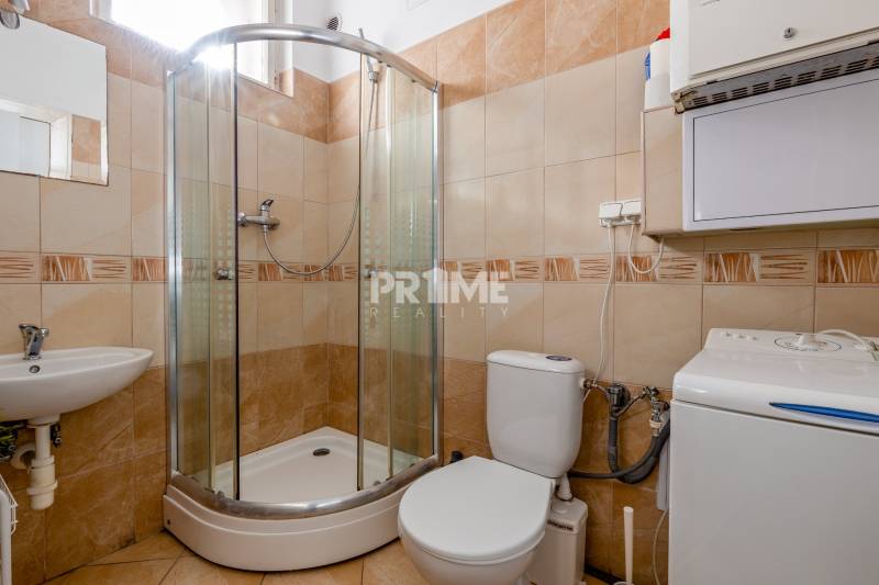 Pekná Garsónka, CENTRUM, REKONŠTRUKCIA,Vajanského nábrežie,Staré Mesto - Kúpeľňa v garsónke s toaletou, sprchovacím kútom a práčkou, obklopená svetlými kachličkami.