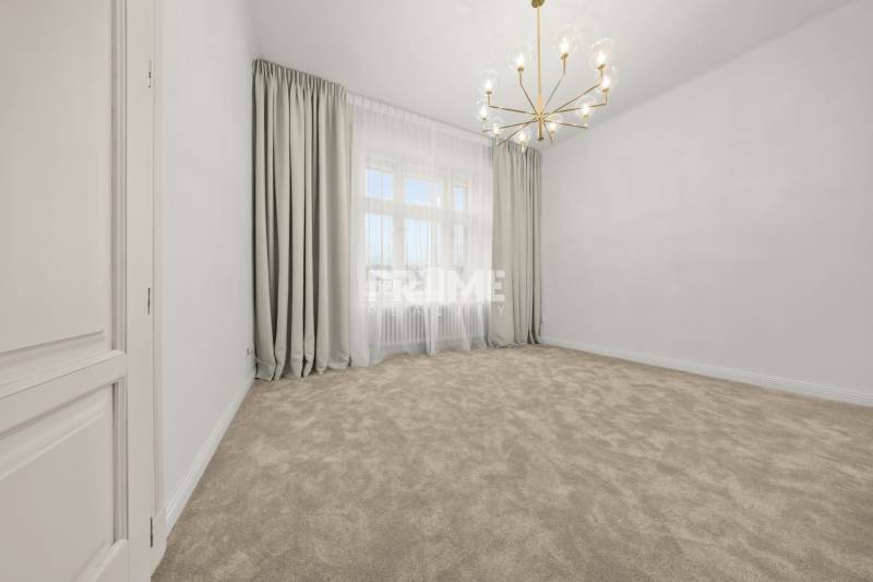  EXKLUZÍVNY, VEĽKOMETRÁŽNY 3i byt ( 130 m2 ), REKONŠTRUKCIA, CENTRUM - Elegantný priestor s kobercom, záclonami a zlatým lustrom v 3-izbovom byte.