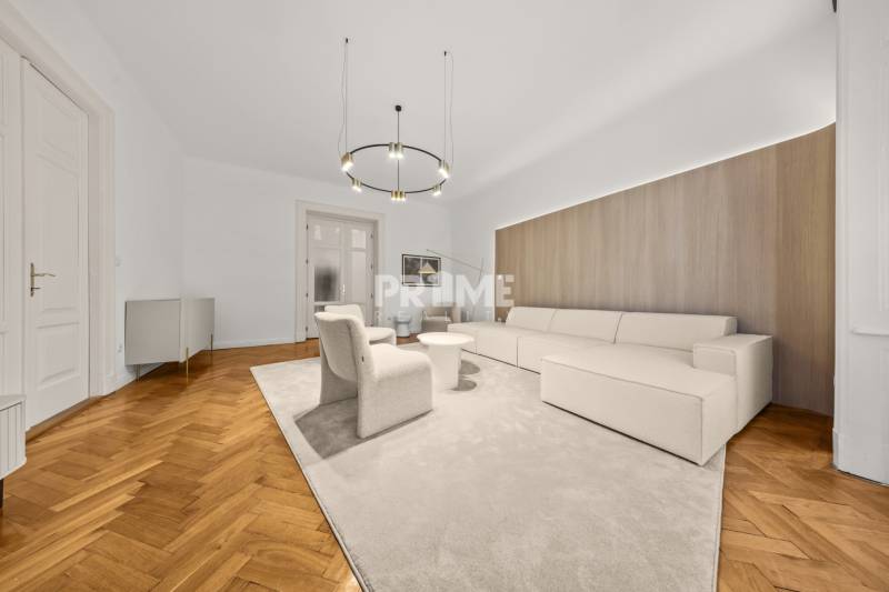  EXKLUZÍVNY, VEĽKOMETRÁŽNY 3i byt ( 130 m2 ), REKONŠTRUKCIA, CENTRUM - Obývacia izba v 3-izbovom byte s béžovou sedačkou a podlahou s dreveným dekorom.