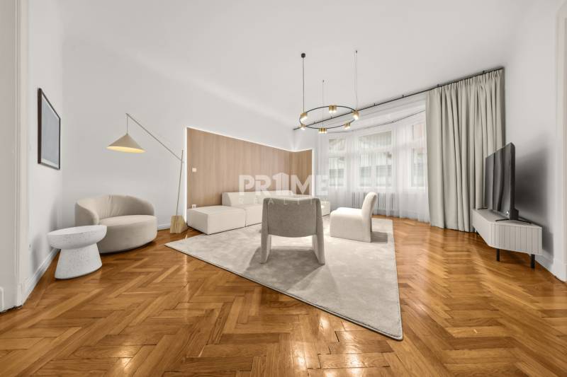  EXKLUZÍVNY, VEĽKOMETRÁŽNY 3i byt ( 130 m2 ), REKONŠTRUKCIA, CENTRUM - Obývacia izba s podlahou s dreveným dekorom, bielym nábytkom a veľkými oknami v 3-izbovom byte.