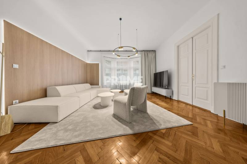  EXKLUZÍVNY, VEĽKOMETRÁŽNY 3i byt ( 130 m2 ), REKONŠTRUKCIA, CENTRUM - Priestranná obývačka v 3-izbovom byte s podlahou s dreveným dekorom a pohodlným sedením.