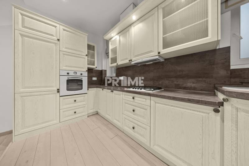  EXKLUZÍVNY, VEĽKOMETRÁŽNY 3i byt ( 130 m2 ), REKONŠTRUKCIA, CENTRUM - Kuchynská linka s bledými skrinkami a zabudovanou rúrou, podlaha s dreveným dekorom.