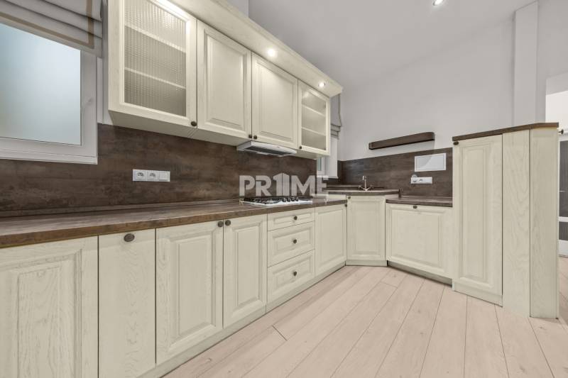  EXKLUZÍVNY, VEĽKOMETRÁŽNY 3i byt ( 130 m2 ), REKONŠTRUKCIA, CENTRUM - Kuchyňa v 3-izbovom byte s bielymi skrinkami a podlahou s dreveným dekorom.