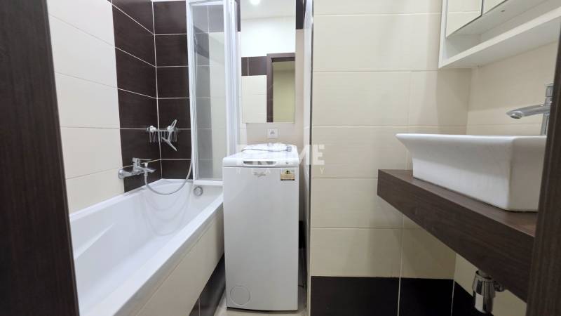 MODERNÝ 2i byt, REKONŠTRUKCIA, KLÍMA, MOZARTOVA ulica, Horský park - Kúpeľňa v 2-izbovom byte s vaňou, práčkou a umývadlom na tmavej doske.