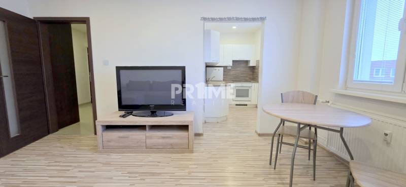 MODERNÝ 2i byt, REKONŠTRUKCIA, KLÍMA, MOZARTOVA ulica, Horský park - Obývacia izba s televízorom a kuchynským kútom, 2-izbový byt s podlahou s dreveným dekorom.