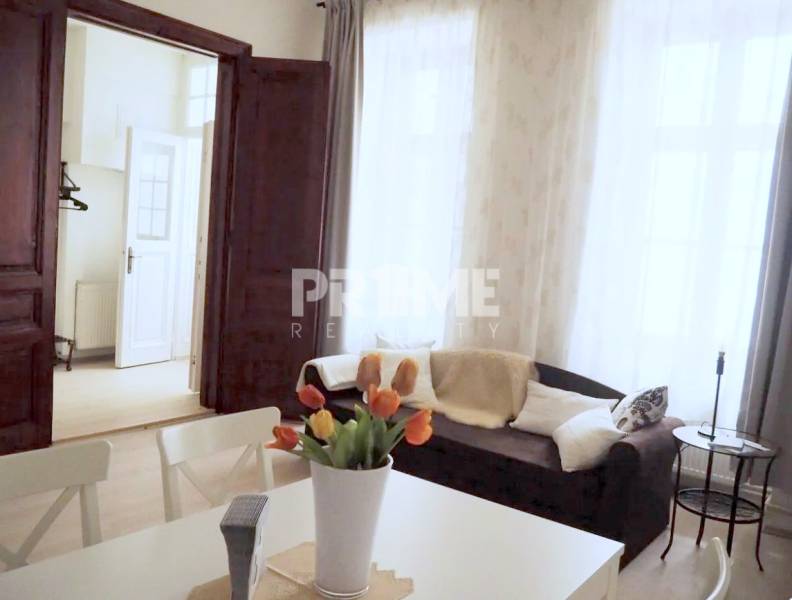 U NÁS !!! Pekný 2i byt, CENTRUM, REKONŠTRUKCIA, Klobučnícka ulica - Obývacia izba 2-izbového bytu na ulici Klobučnícka s pohodlným gaučom a kvetinovou dekoráciou.