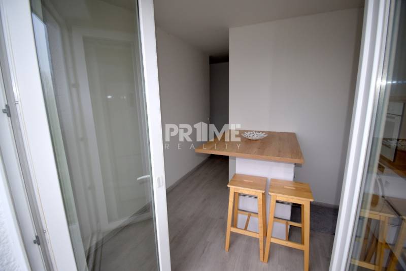 SLNEČNÝ 2i byt, REKONŠTRUKCIA, 2 X SAMOST.IZBA, BALKÓN, Haburská ulica - Balkón s barovým pultom a stoličkami v 2-izbovom byte, podlaha s dreveným dekorom.