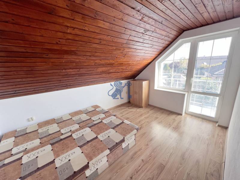 Na prenájom 3i byt v rodinom dome so záhradou - Vojenská ul. Rovinka - Podkrovný 3-izbový byt s dreveným stropom, posteľou a oknom na Vojenskej ulici.