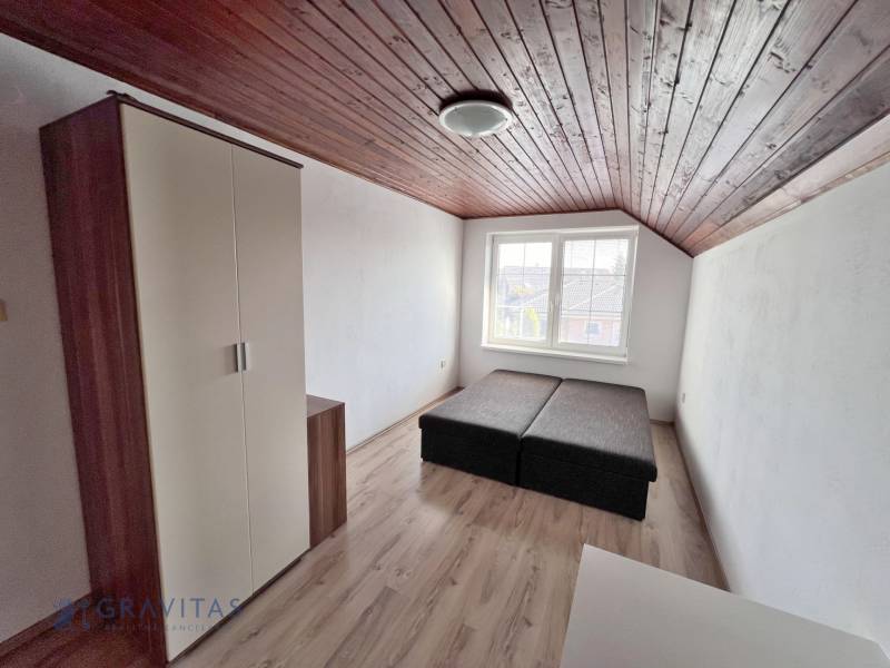 Na prenájom 3i byt v rodinom dome so záhradou - Vojenská ul. Rovinka - Izba so šikmým dreveným stropom, posteľou a skriňou, výhľad smerom na ulicu Vojenská.
