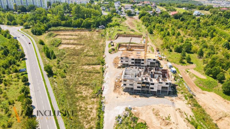 1i - 2i - 3i BYTY V NOVOSTAVBE | NITRA - MLYNARCE - Stavba pri Kmeťovej ulici v Nitre obklopená zeleňou a cestou.