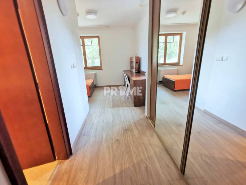 PEKNÁ GARSÓNKA, NOVOSTAVBA, KLÍMA, DRAŽDIAK HAUS, Antolská ulica - Garsónka s podlahou s dreveným dekorom, veľkým oknom a pracovným stolom.