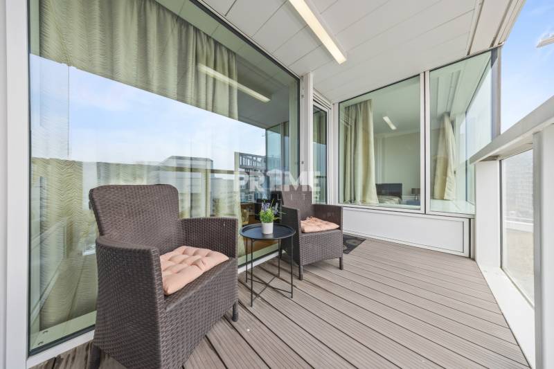 KRÁSNY 2i byt, KLÍMA, LOGGIA,VÝHĽAD,PANORAMA CITY, Landererova ulica - Balkón v 2-izbovom byte s ratanovými kreslami a stolíkom, podlaha s dreveným dekorom.