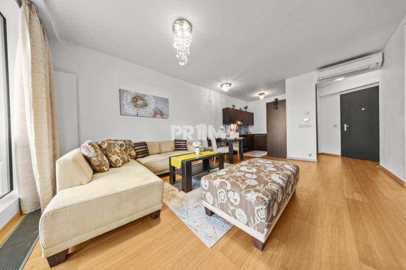 KRÁSNY 2i byt, KLÍMA, LOGGIA,VÝHĽAD,PANORAMA CITY, Landererova ulica - Obývačka s rohovou sedačkou, stolíkom a podlahou s dreveným dekorom v 2-izbovom byte.