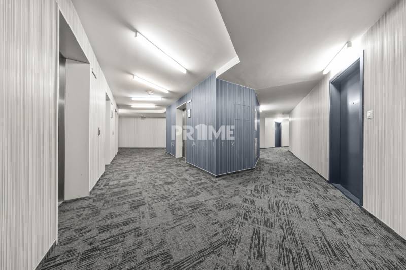 KRÁSNY 2i byt, KLÍMA, LOGGIA,VÝHĽAD,PANORAMA CITY, Landererova ulica - Chodba s výťahmi, svetlými stenami a šedým kobercom v Bratislave na Landererovej.