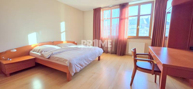 VEĽKOMETRÁŽNY 3i byt, 3 x NEPRIECHODNÁ IZBA, KLÍMA, BALKÓN, Nám.SNP - Svetlá spálňa s podlahou s dreveným dekorom, manželskou posteľou a pracovným stolom v 3-izbovom byte.