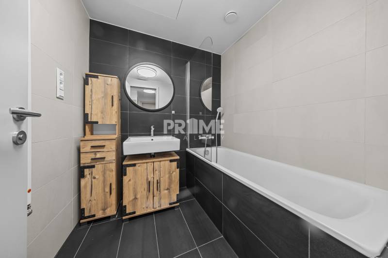 ŠTÝLOVÝ 2i byt,SKY PARK,VÝHĽAD,LOGGIA,PARKING,VEŽA II,Továrenská ul. - Kúpeľňa v 2-izbovom byte s tmavými obkladmi a dreveným nábytkom.