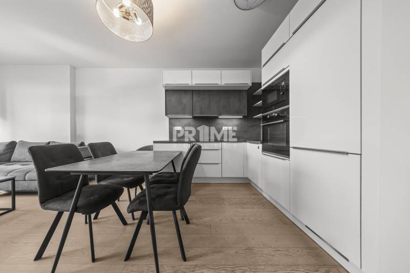 ŠTÝLOVÝ 2i byt,SKY PARK,VÝHĽAD,LOGGIA,PARKING,VEŽA II,Továrenská ul. - Kuchyňa v 2-izbovom byte s jedálenským stolom, čiernymi stoličkami a podlahou s dreveným dekorom.
