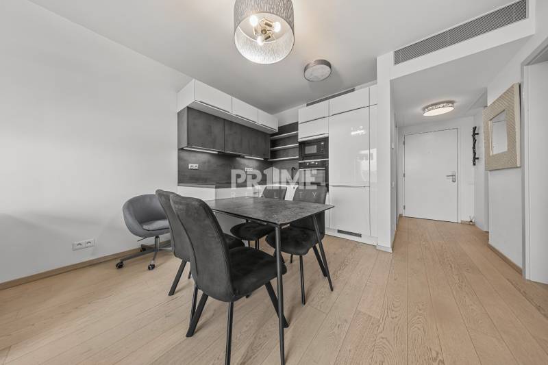 ŠTÝLOVÝ 2i byt,SKY PARK,VÝHĽAD,LOGGIA,PARKING,VEŽA II,Továrenská ul. - Kuchyňa v 2-izbovom byte so stôlmi a stoličkami, podlaha s dreveným dekorom.