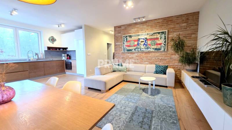 LUXUSNÝ 3i byt, TERASA, PARKING, KLÍMA, ZELENÁ HORKA, Ďumbierska ulica - Obývacia izba v 2-izbovom byte s tehlovou stenou a podlahou s dreveným dekorom.