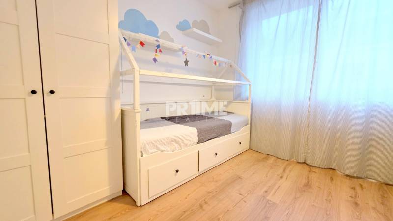 LUXUSNÝ 3i byt, TERASA, PARKING, KLÍMA, ZELENÁ HORKA, Ďumbierska ulica - Detská izba s posteľou, šatníkom a podlahou s dreveným dekorom v 2-izbovom byte.