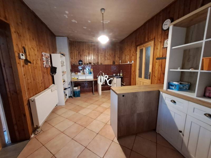 Šikovná drevenica pod lesom Slovenské Pravno  - Kuchyňa v rodinnom dome s dreveným obkladom a keramickou podlahou.