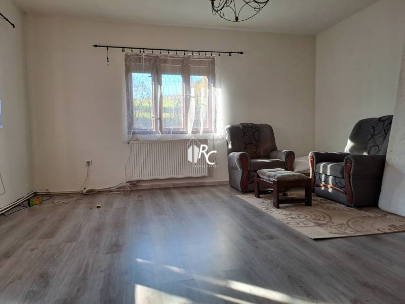 Šikovná drevenica pod lesom Slovenské Pravno  - Obývacia izba s kreslami a podlahou s dreveným dekorom v rodinnom dome.