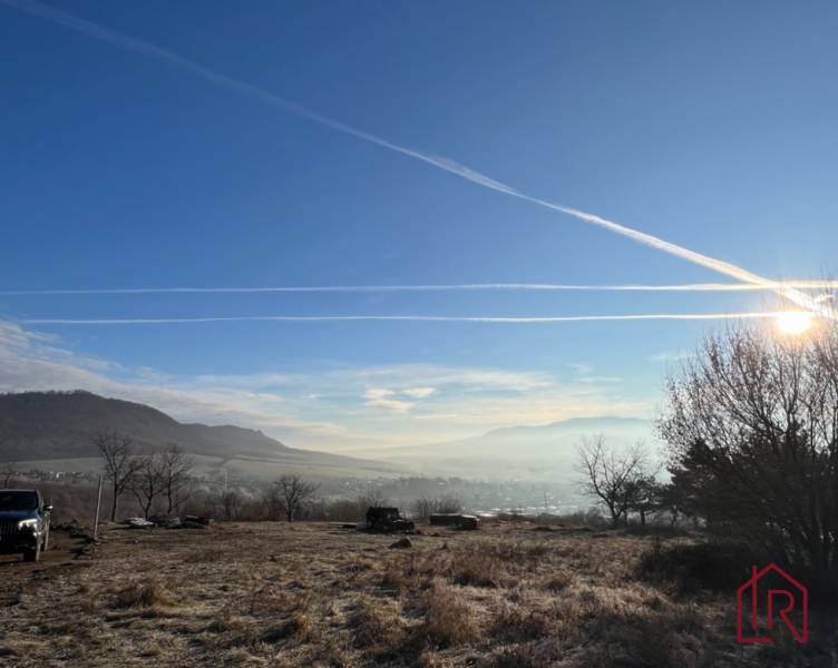 KH-1051, Pozemok, záhrada, Prešov, Fintice - Krajina v Záhradách Fintíc s kopcami, modrou oblohou a slnečnými lúčmi.