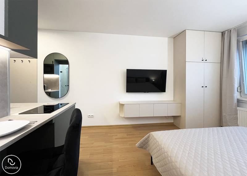 Bez provízie | Na prenájom dizajnové štúdio v Ružinove - Garsónka s TV na stene, podnikoverská podlaha, posteľ a kuchyňa.