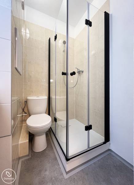 Bez provízie | Na prenájom dizajnové štúdio v Ružinove - Kúpeľňa v garsónke s toaletou a sprchovacím kútom, dlažba svetlej farby.