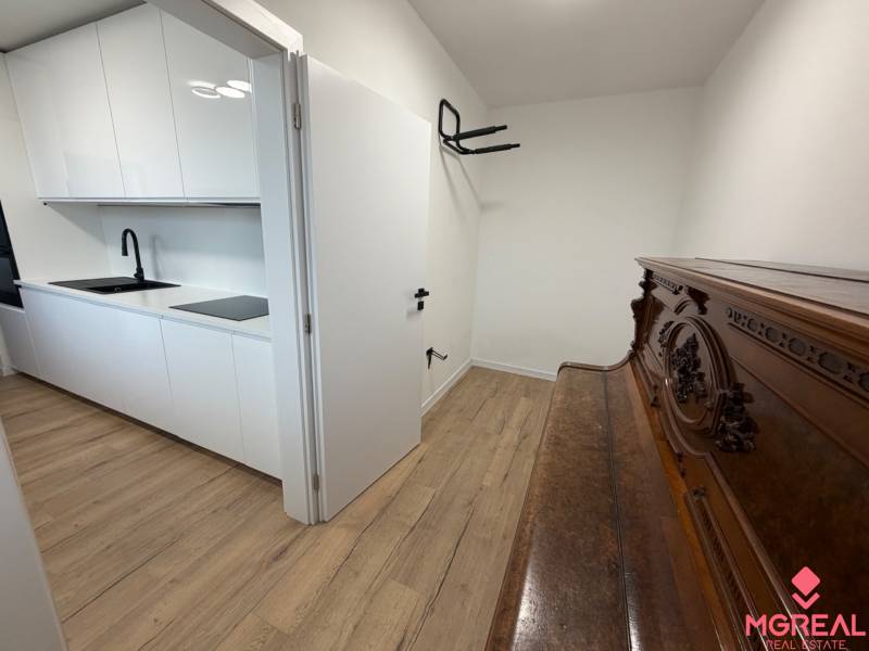3 izbový byt s balkónom Topoľčany / PRENAJOM  - Biela kuchyňa s dreveným dekorom podlahy, vedľa klavír, 3-izbový byt.