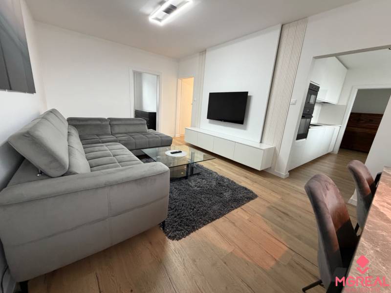 3 izbový byt s balkónom Topoľčany / PRENAJOM  - Obývačka so sivou sedačkou, televízorom a podlahou s dreveným dekorom v 3-izbovom byte.