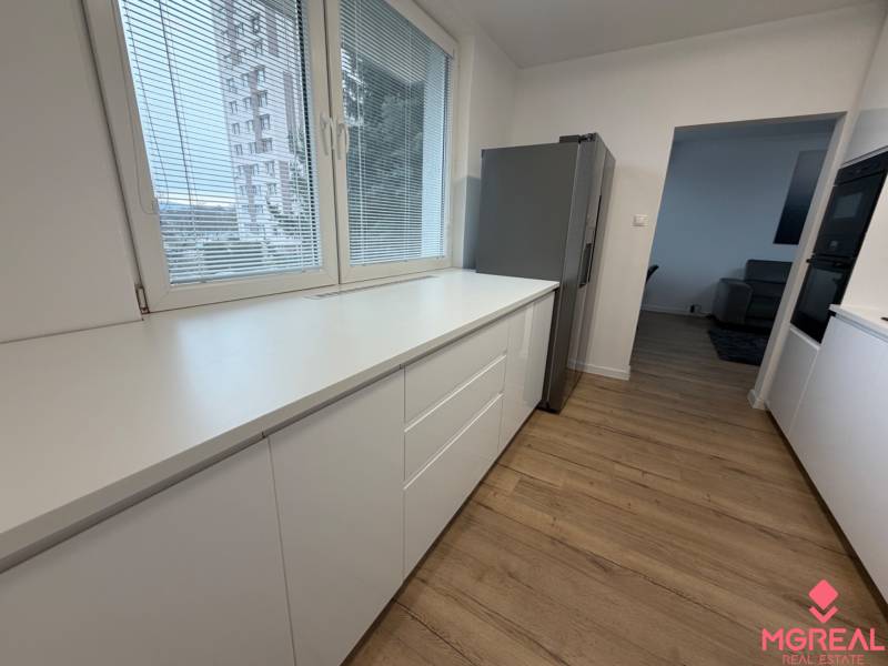 3 izbový byt s balkónom Topoľčany / PRENAJOM  - Kuchyňa 3-izbového bytu s bielymi skrinkami a podlahou s dreveným dekorom.
